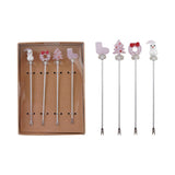 A boxed set of four stainless steel appetizer picks topped with hand-blown glass holiday icons