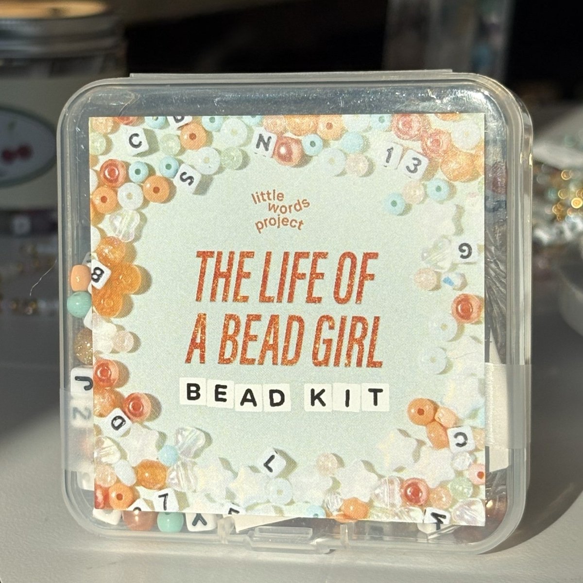 Bead kit packaging with decorative text and bead designs on a light background