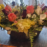 Floral arrangement on a glass table with a wooden floor background