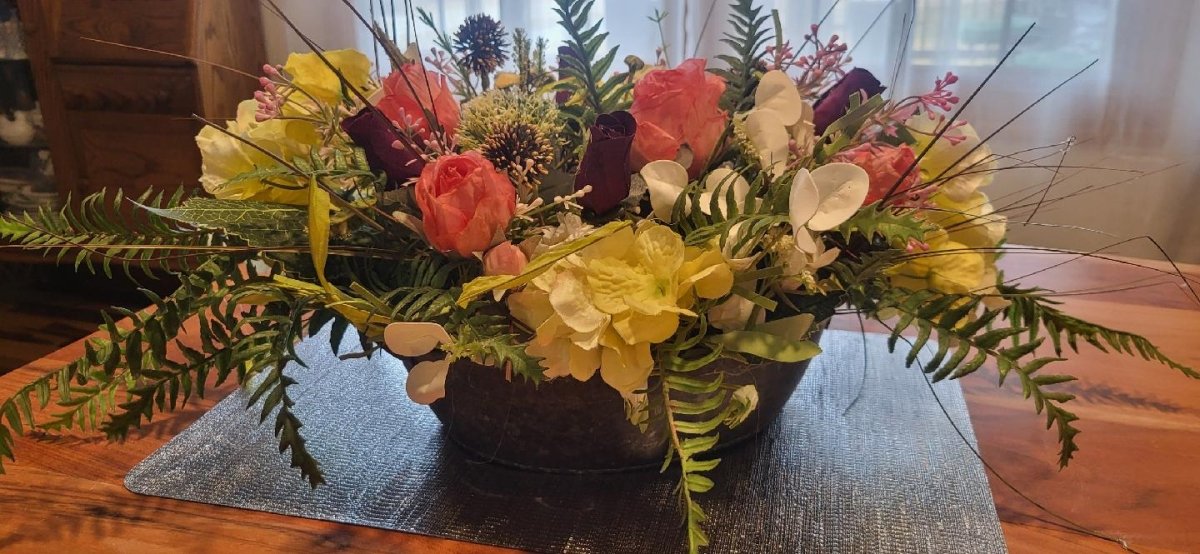 Floral arrangement on a glass table with a wooden floor background